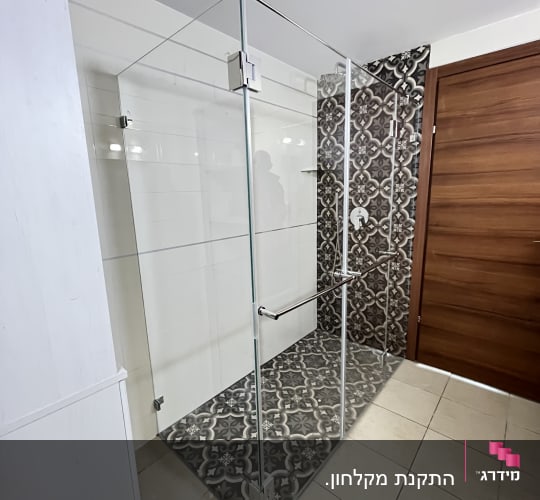 מקלחון זכוכית עם דלת עץ ורצפה מעוצבת